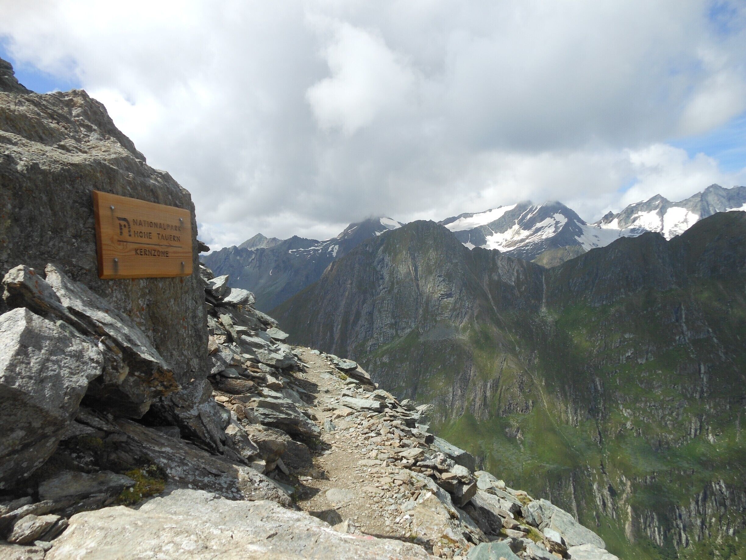 A rocky mountain trail with a sign for the Nationalpark Home Tavern in the Kernzone.