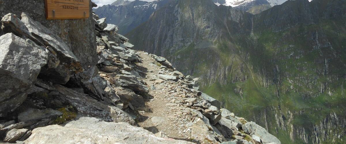 A rocky mountain trail with a sign for the Nationalpark Home Tavern in the Kernzone.