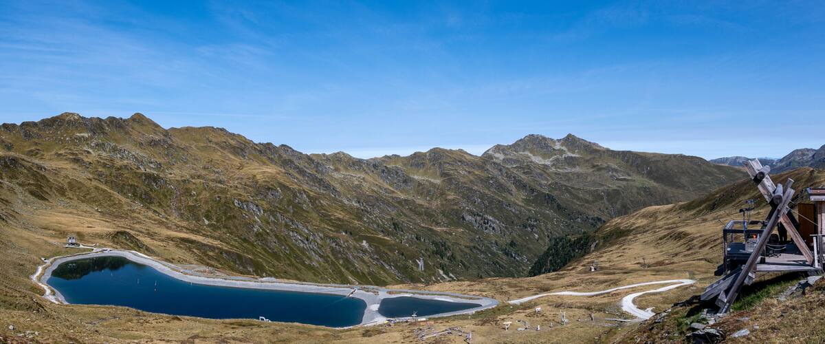 A mountainous landscape with a lake and a wooden viewing platform.