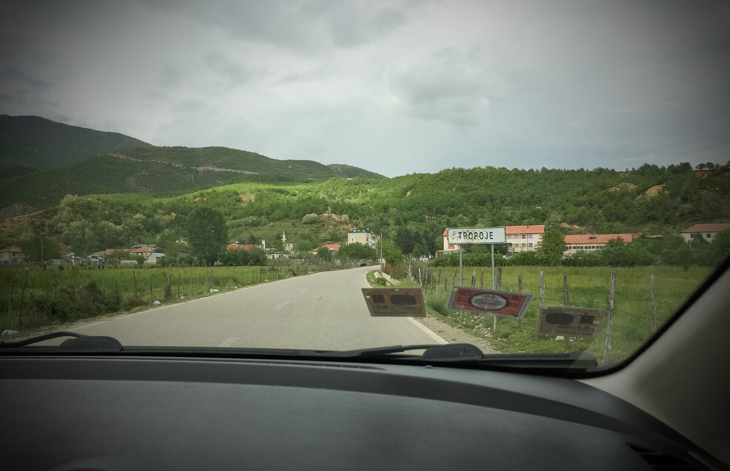 A road through a hilly area with houses and a sign reading "TROPOE".