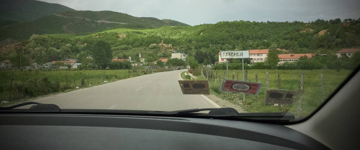 A road through a hilly area with houses and a sign reading "TROPOE".