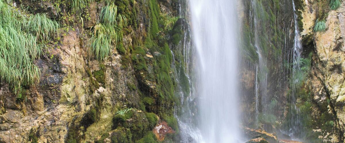 A waterfall cascading over moss-covered rocks into a clear pool.