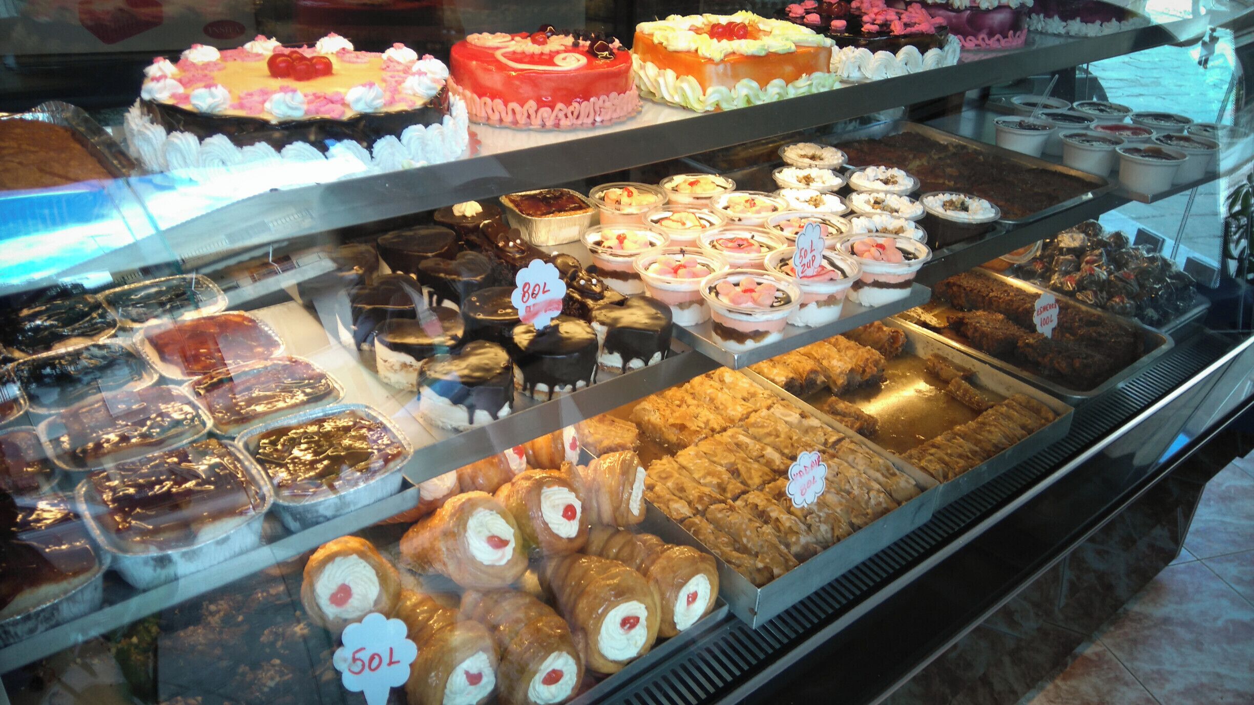 A bakery display case with various cakes, pastries, and desserts.