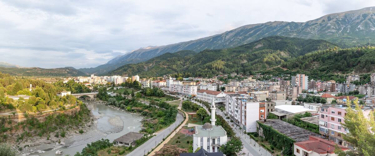A river flowing through a town with mountains in the background.