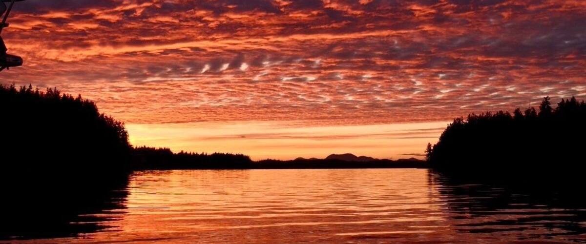 A sunset over a calm lake with red and orange clouds.