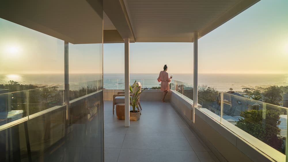 Woman relaxing on sunny balcony with sunset ocean view