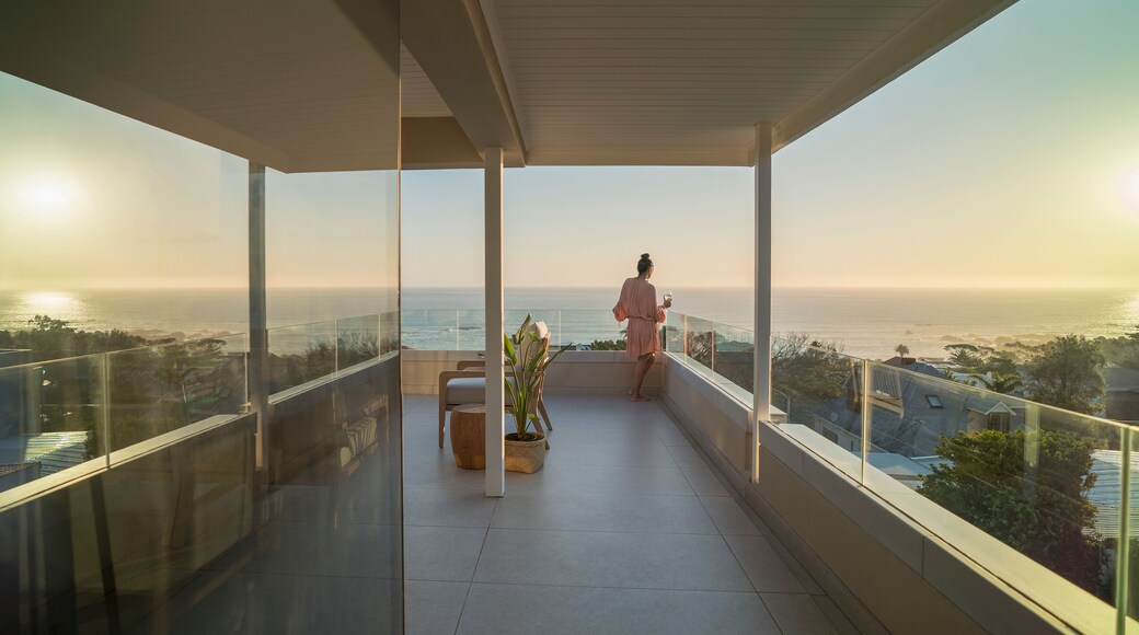 Woman relaxing on sunny balcony with sunset ocean view
