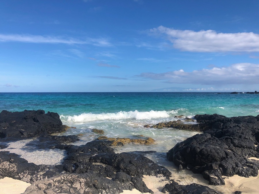 A rocky shoreline with clear turquoise water and a clear sky.