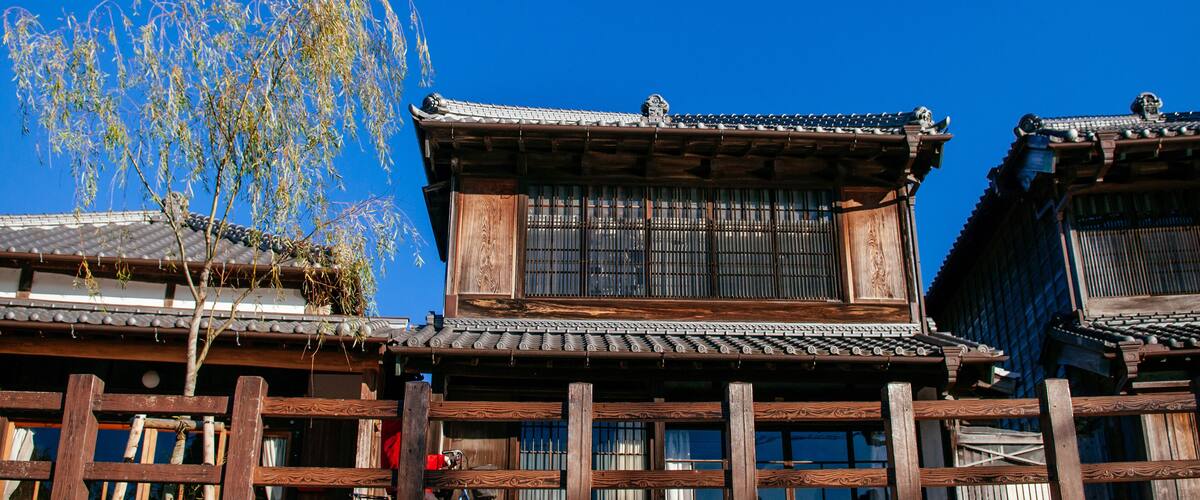 Traditional wooden buildings with tiled roofs and a clear blue sky.