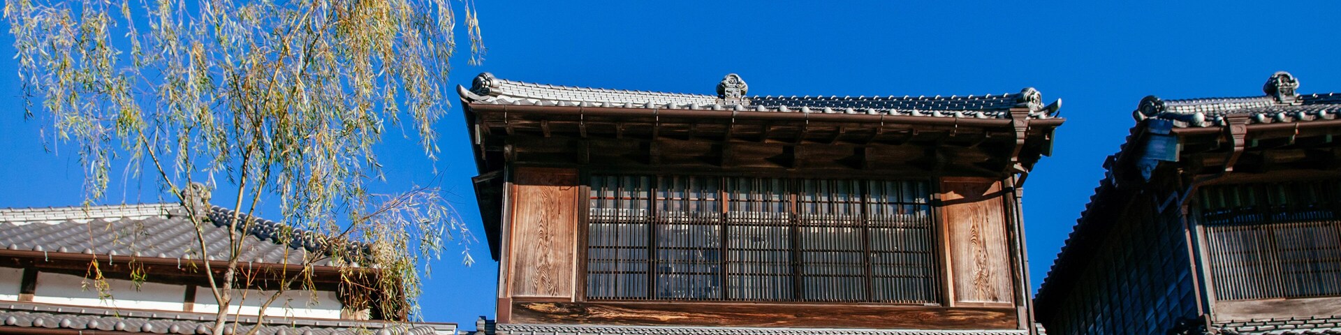Traditional wooden buildings with tiled roofs and a clear blue sky.