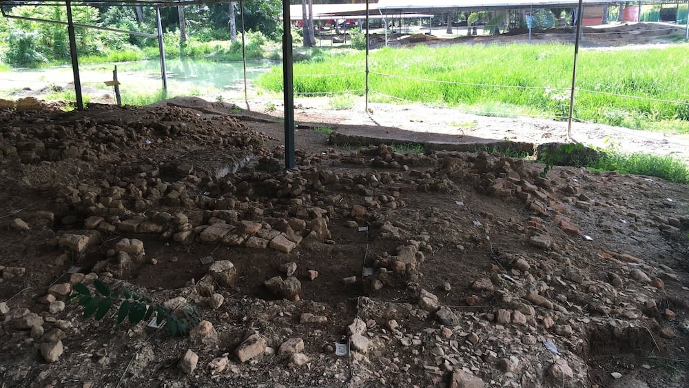 An archaeological site with exposed ruins and a covered shelter.
