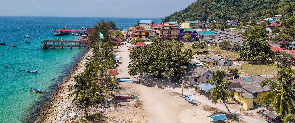 A coastal town with colorful buildings, a pier, and boats on the turquoise sea.