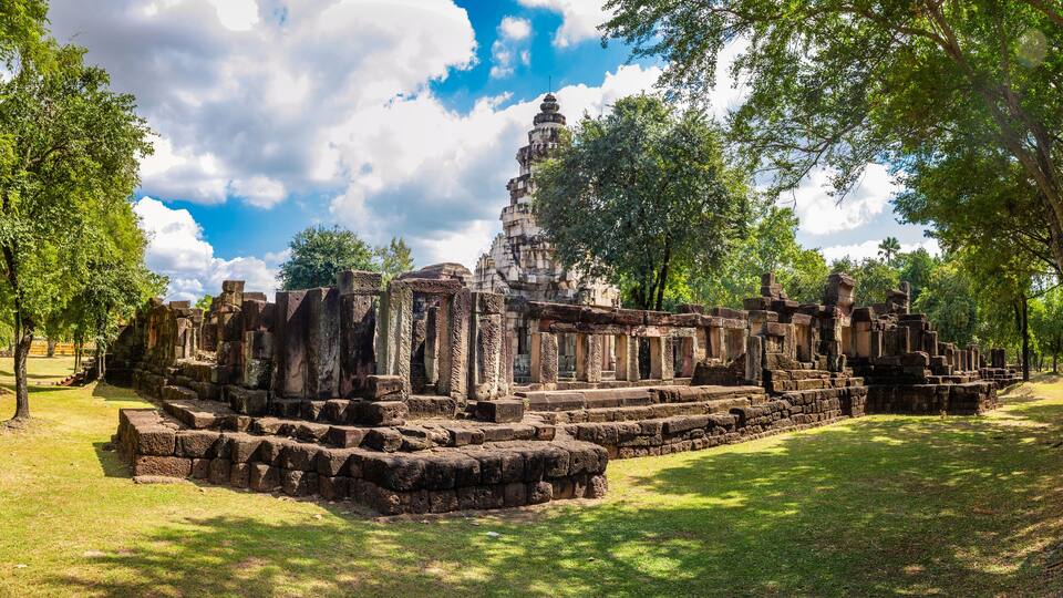 Ancient stone ruins with a central stupa surrounded by trees.