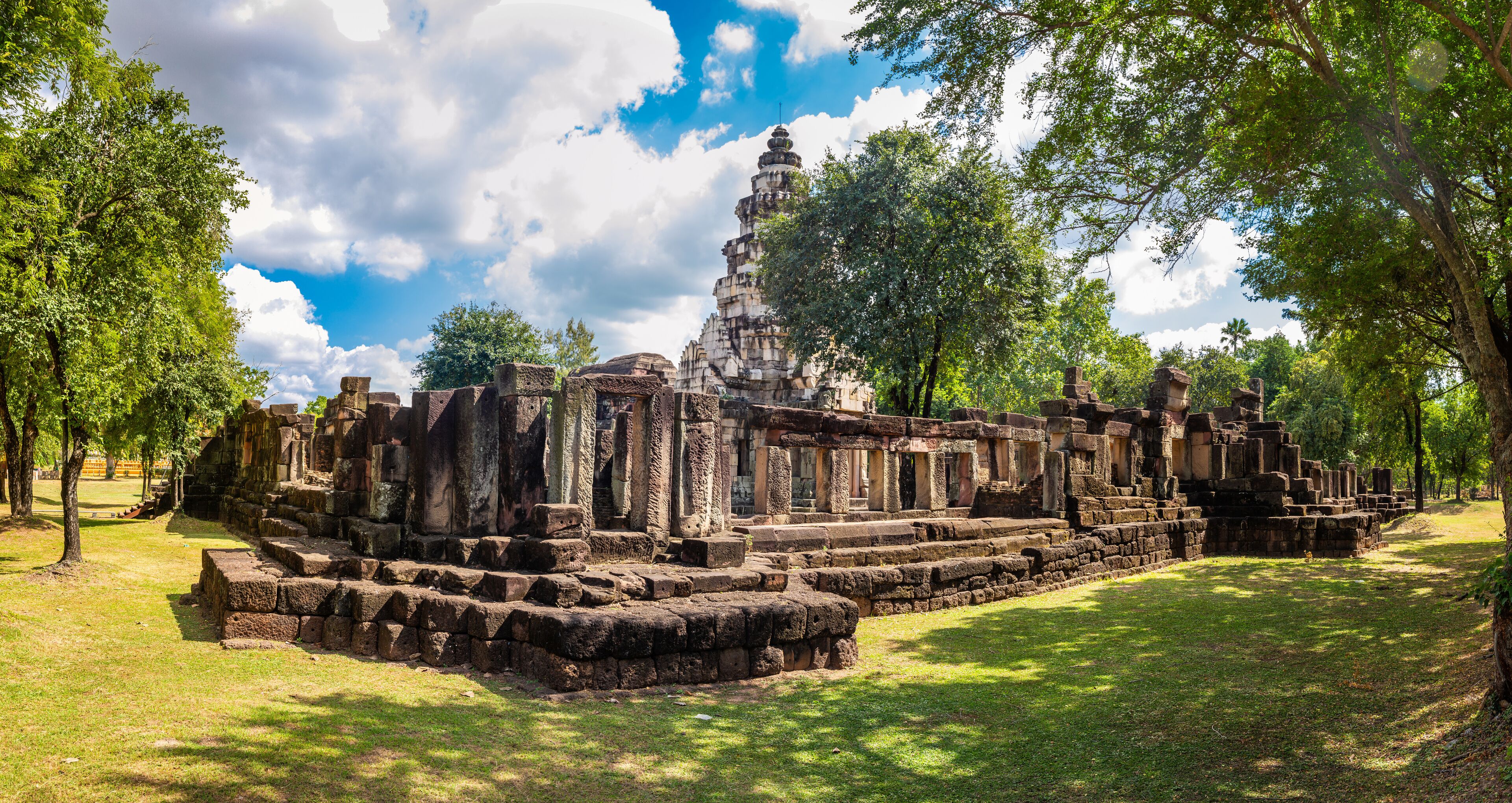 Ancient stone ruins with a central stupa surrounded by trees.