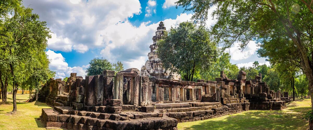 Ancient stone ruins with a central stupa surrounded by trees.