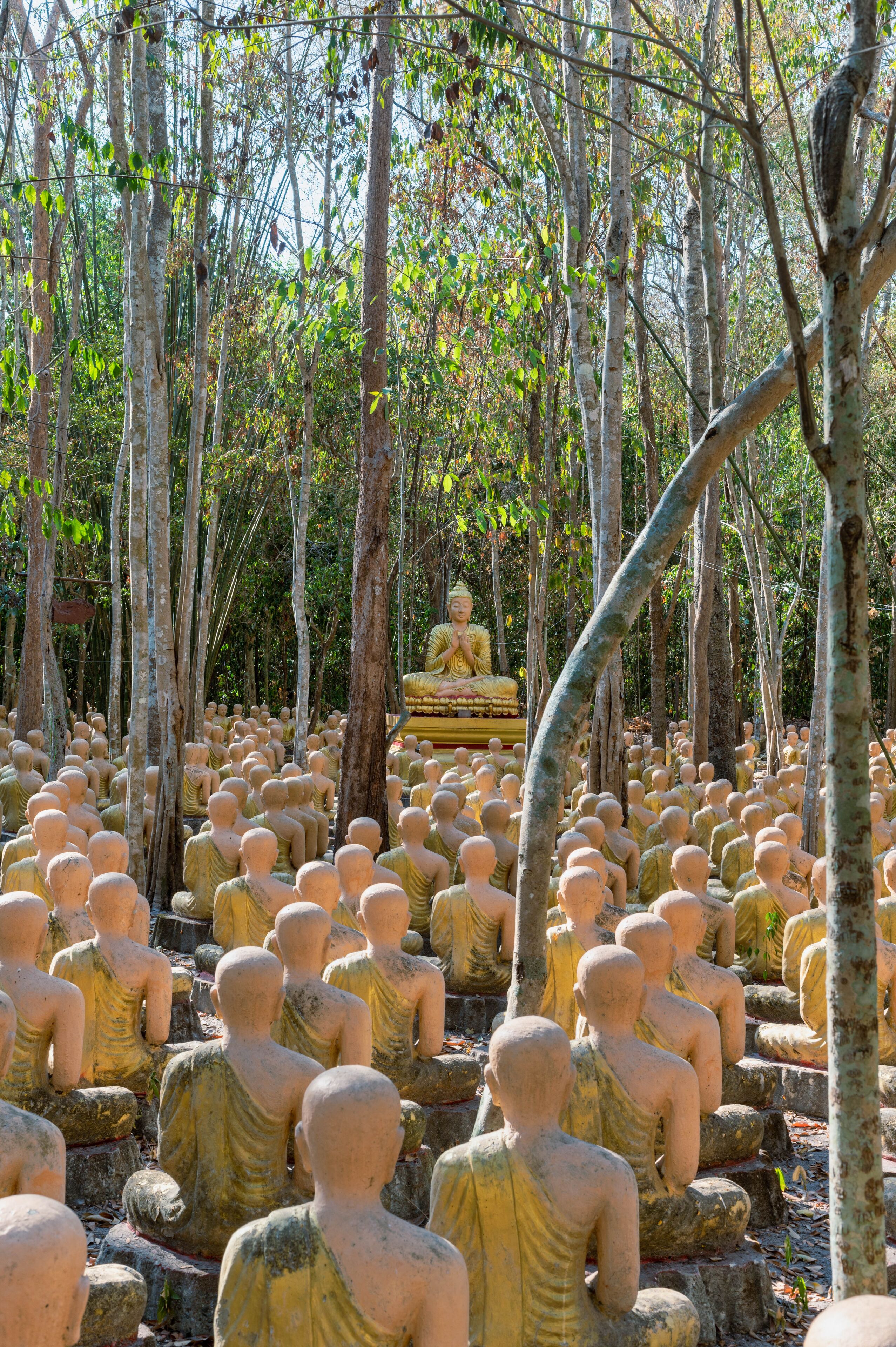 A forest of Buddha statues with a large Buddha statue in the background.