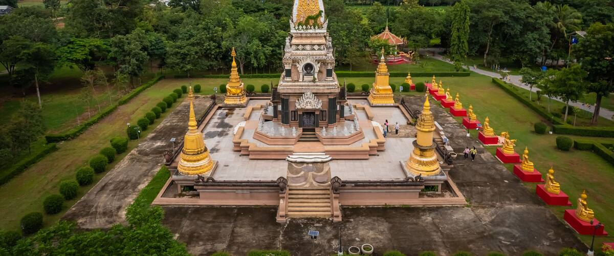 A temple complex with a central stupa, surrounded by smaller golden stupas and a large pagoda.