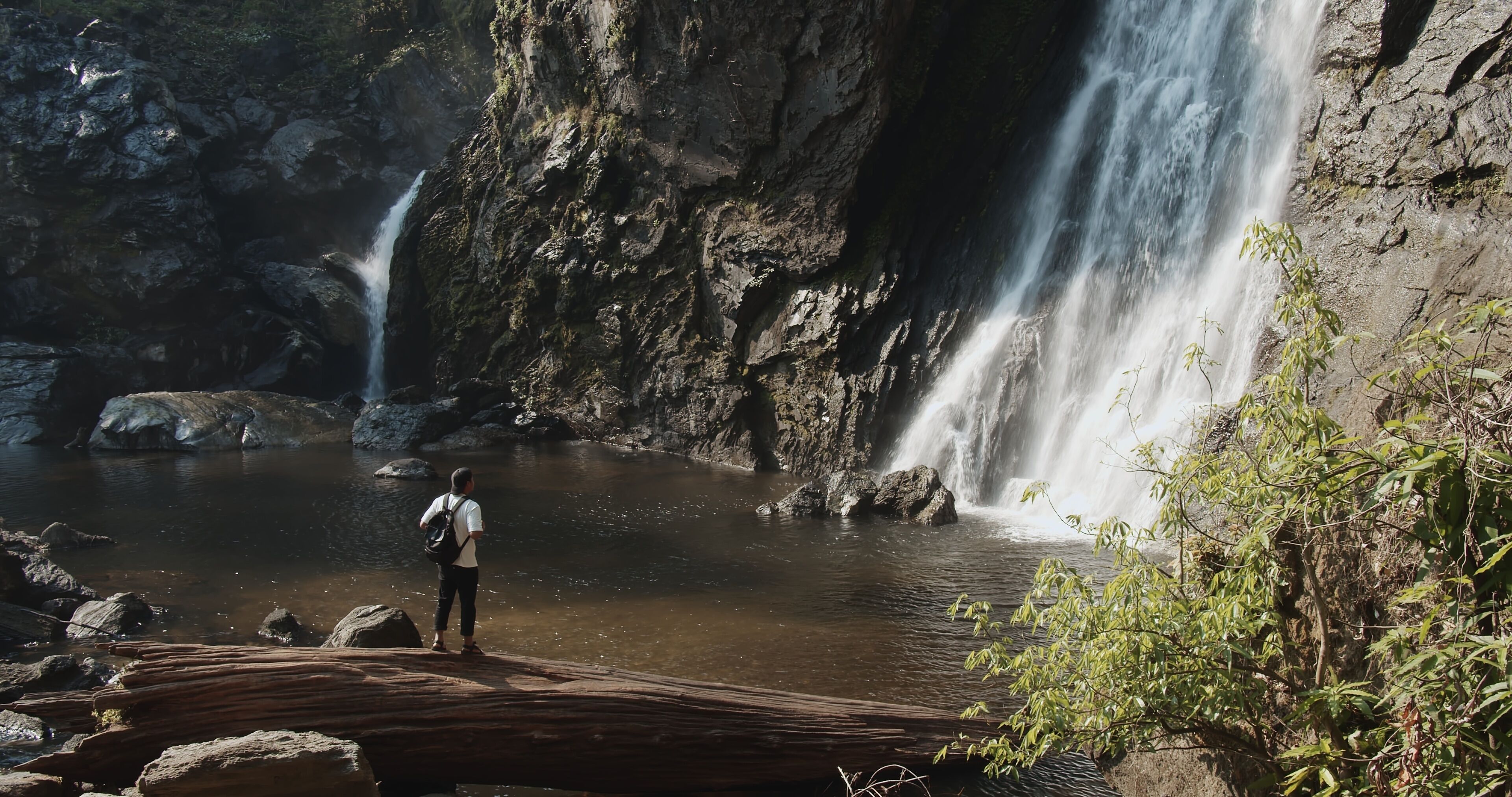 Young tourist traveler man standing enjoy wonderful tropical amazing Khlong Lan Waterfall in Klong Lan National Park, beautiful falling water at Kamphaeng Phet, Thailand, Travel vacation nature