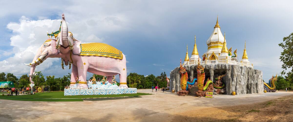 A large pink elephant statue with golden decorations, a temple with multiple spires, and a dragon statue.
