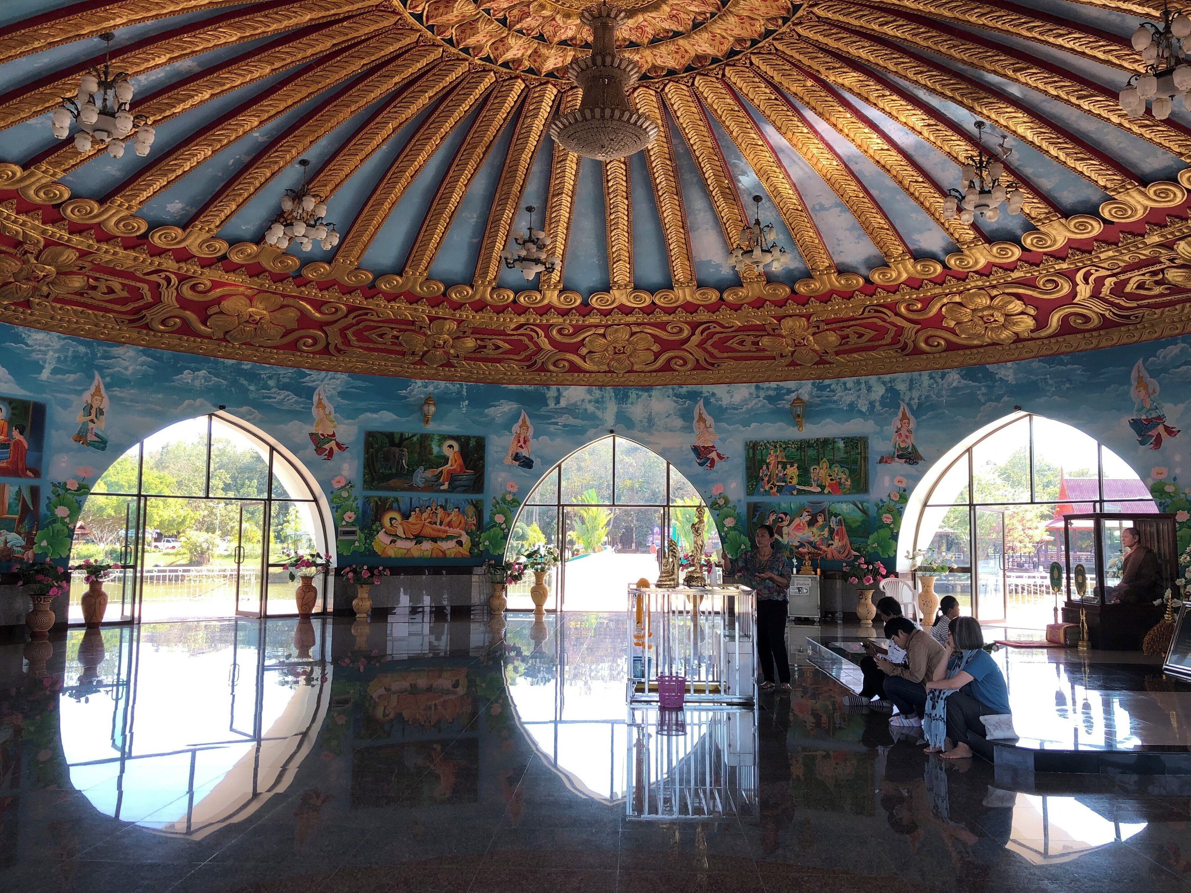A grand hall with ornate golden ceiling, large arched windows, and detailed murals.