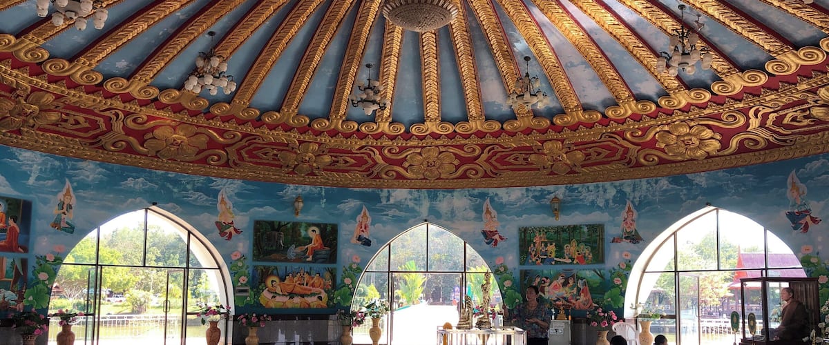 A grand hall with ornate golden ceiling, large arched windows, and detailed murals.