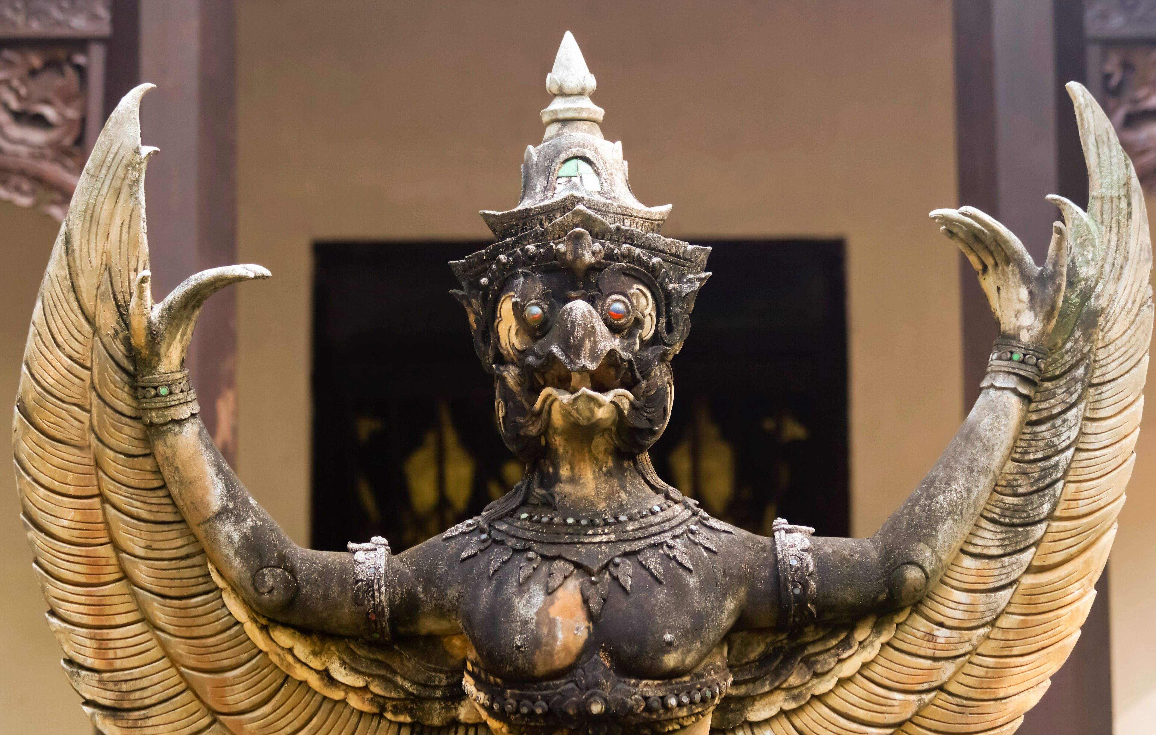 A statue with wings and a pointed hat, set against a plain background.