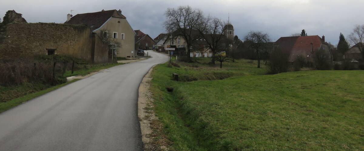 A rural road curving through a village with stone buildings and a church tower.