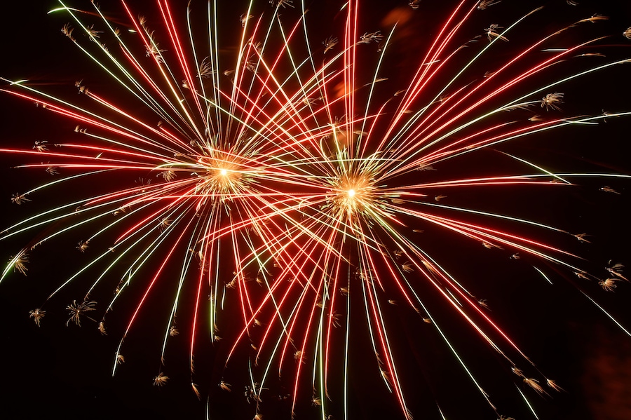 Fuegos artificiales con estelas rojas, verdes y amarillas sobre un cielo oscuro.