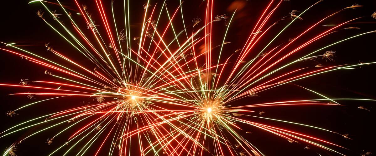 Fireworks with red, green, and yellow trails against a dark sky.