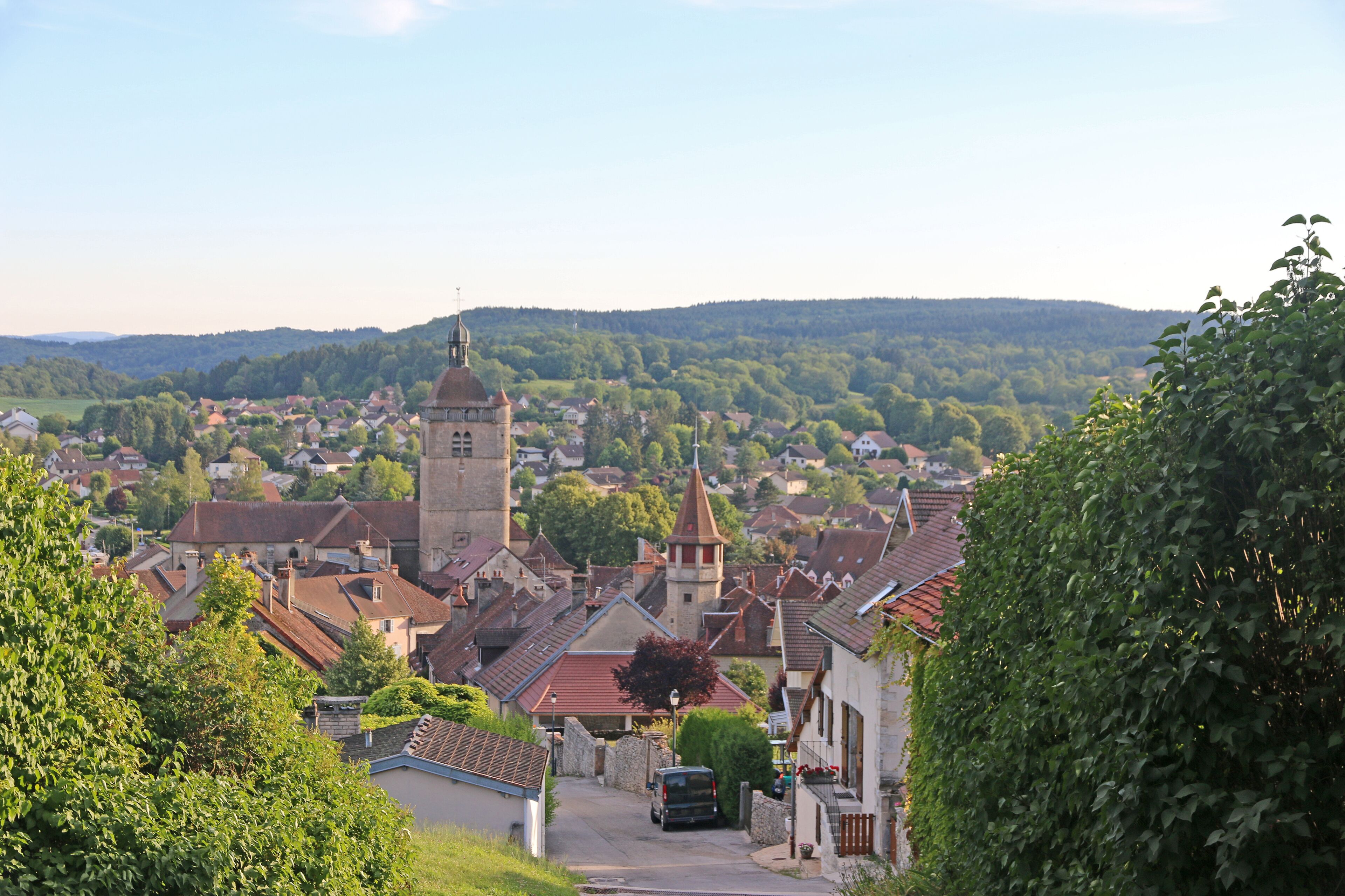 A town with a prominent church tower, surrounded by houses and greenery.