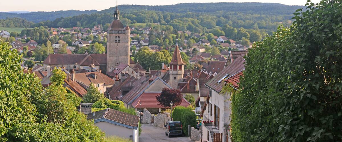 A town with a prominent church tower, surrounded by houses and greenery.
