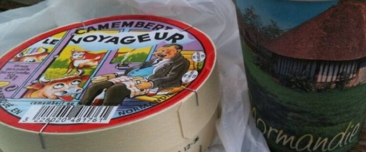A cheese wheel and a paper cup with a landscape design.