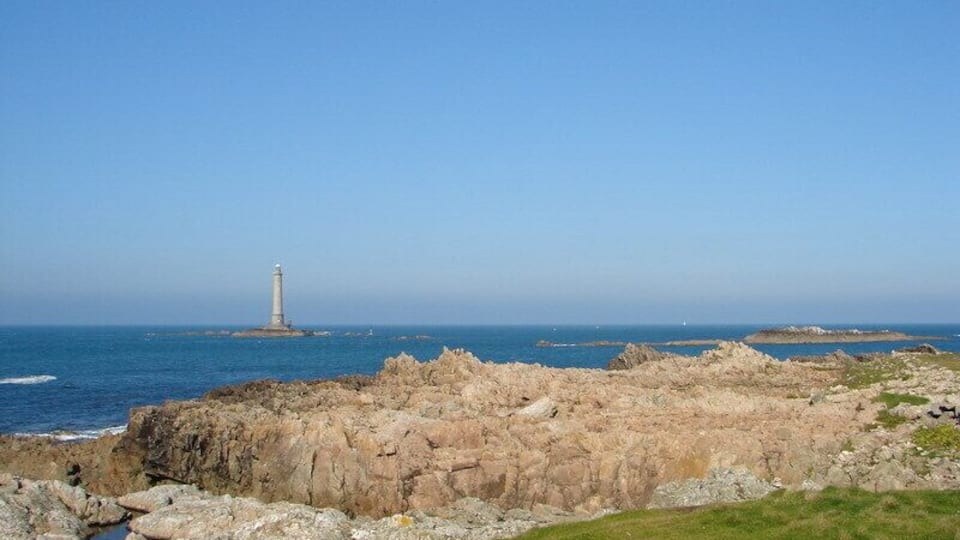 A rocky coastline with a lighthouse in the distance.