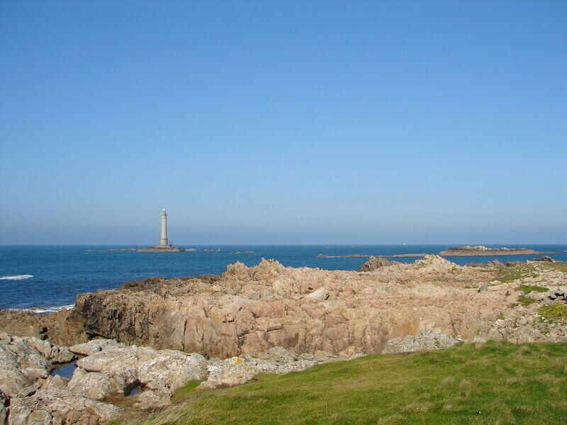 A rocky coastline with a lighthouse in the distance.