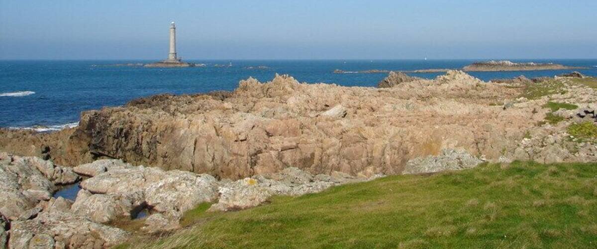 A rocky coastline with a lighthouse in the distance.