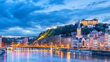 Um rio com uma ponte, edifícios históricos e um castelo numa colina.