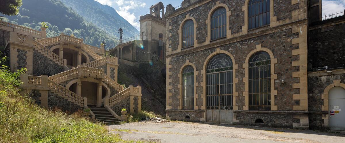 A historic stone building with arched windows and a staircase leading up to a balcony.