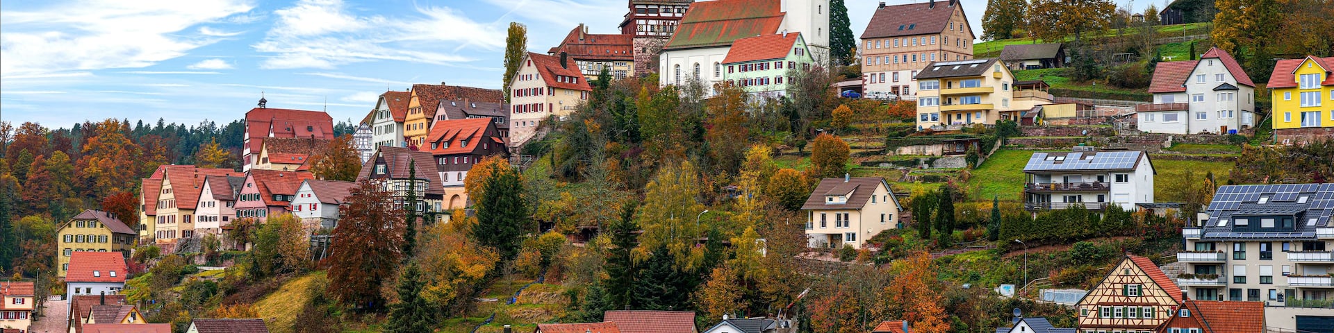 A hillside town with colorful houses, a church, and autumn foliage.