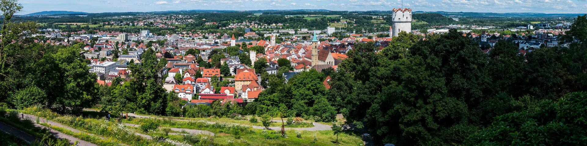 A town with red-roofed buildings, a prominent tower, and a clear blue sky.