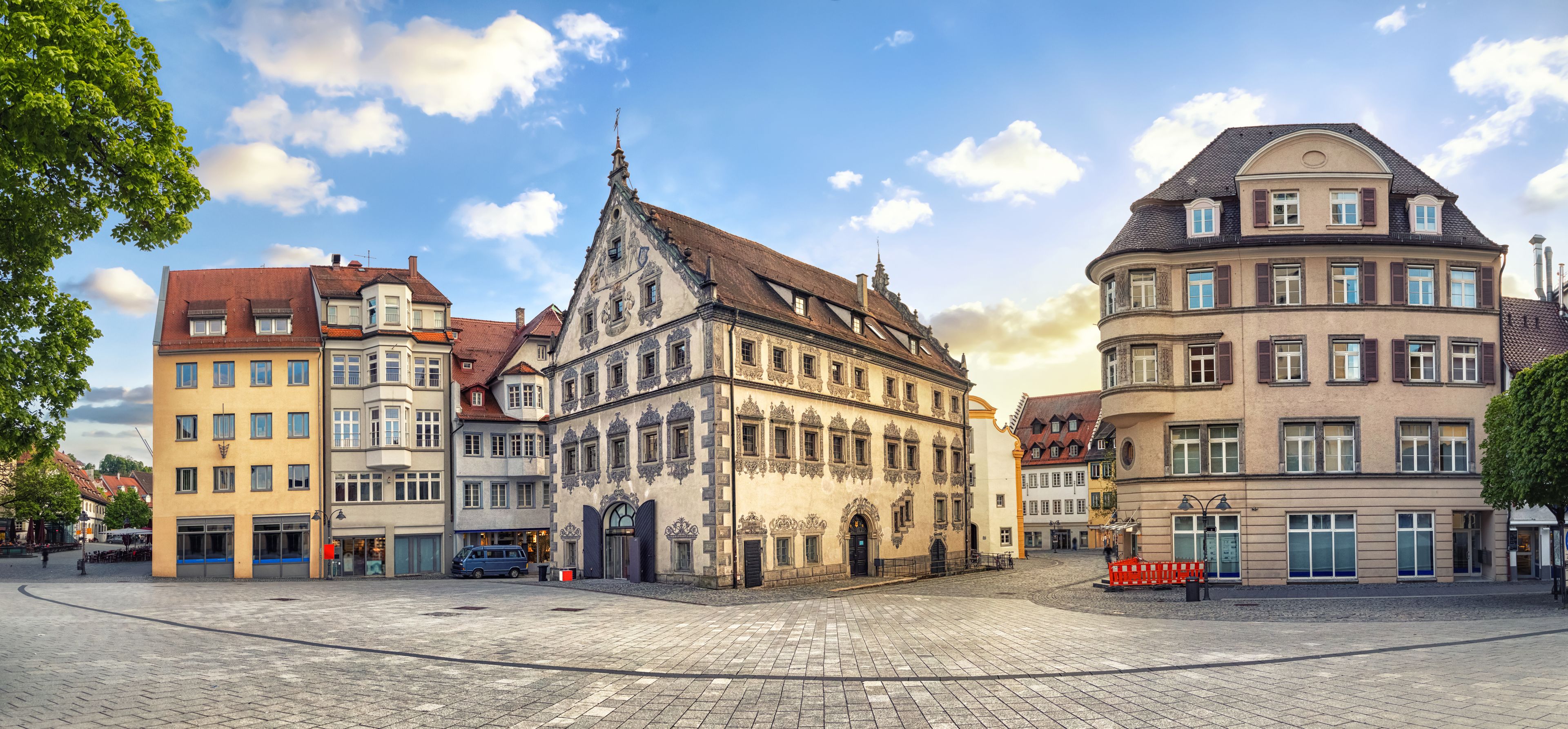 A cobblestone square with historic buildings, a church, and a clear blue sky.