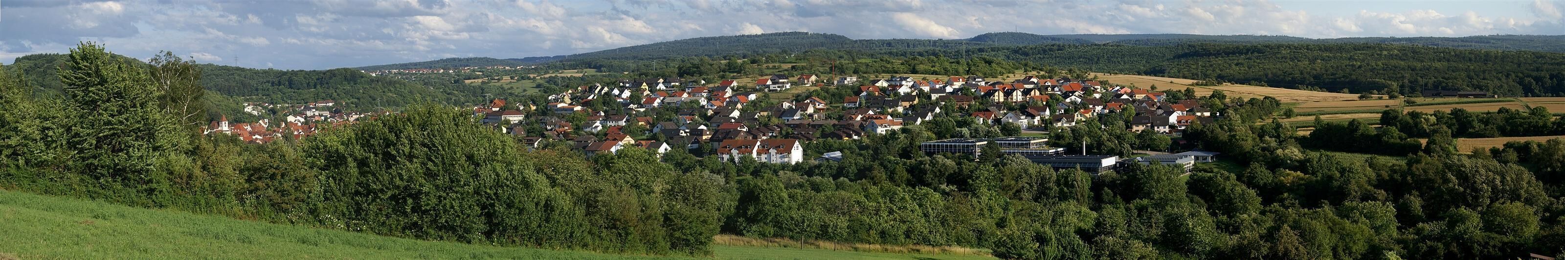 A village nestled in a valley surrounded by forested hills.