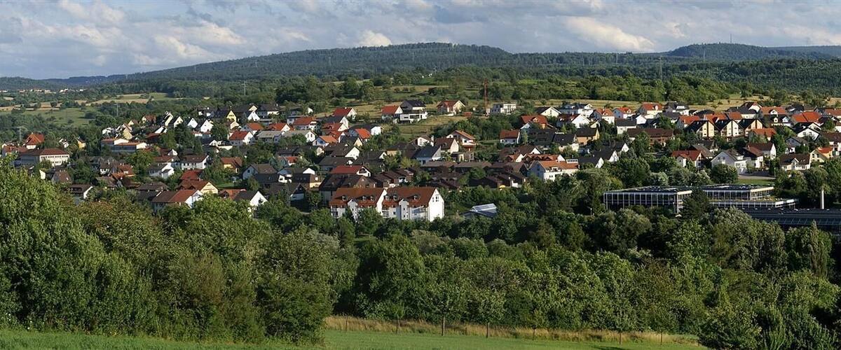 A village nestled in a valley surrounded by forested hills.