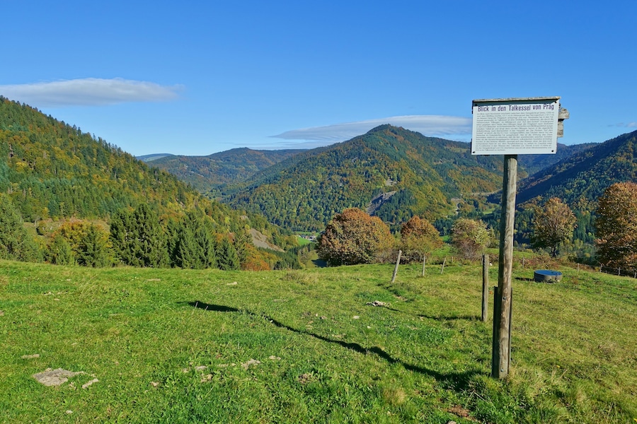 Ein Wegweiser in einem grünen Feld mit einer bergigen Kulisse.