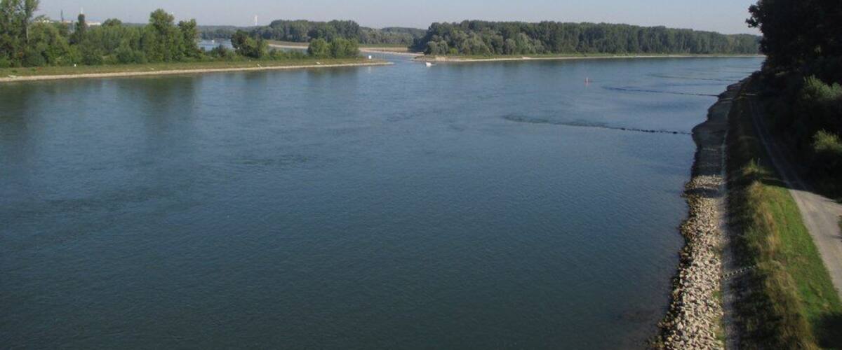A river with a rocky shoreline and a road parallel to it.
