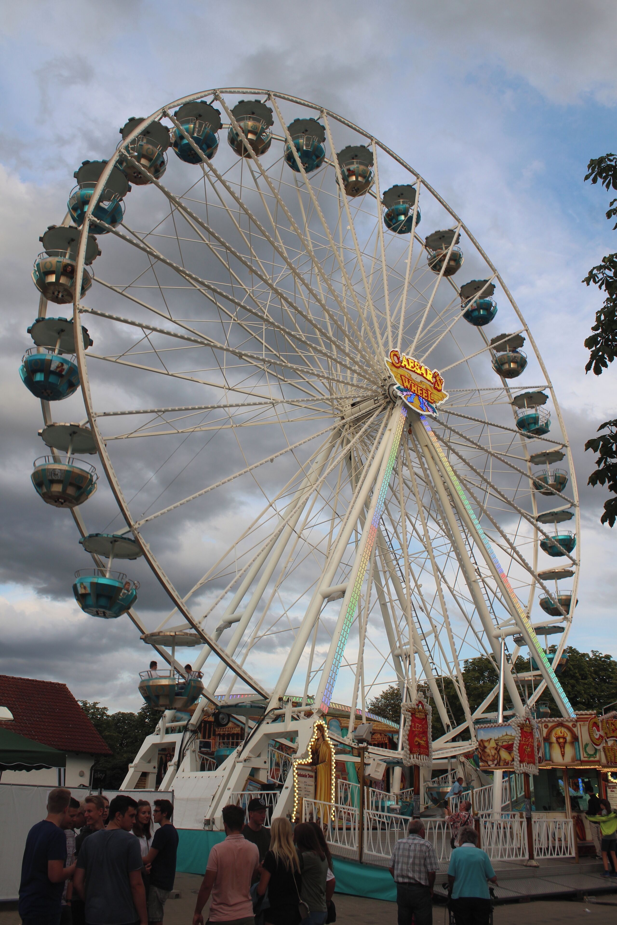 A large Ferris wheel with cabins, a sign reading "Carousel Wheel," and people around it.