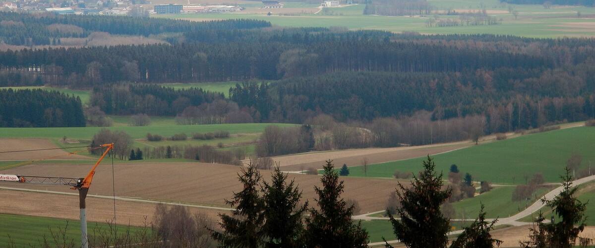 A rural landscape with fields, trees, and a distant village.