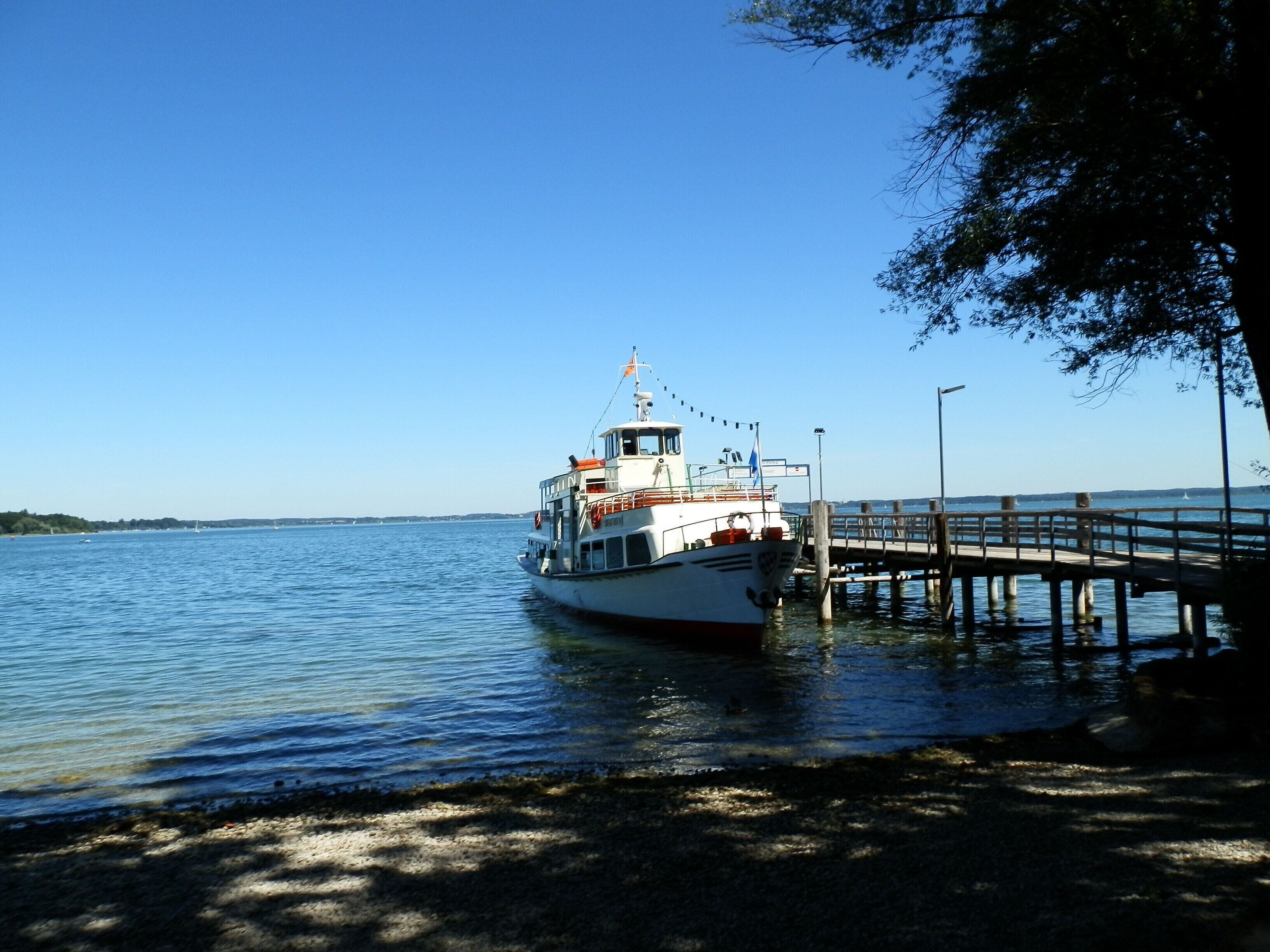 A white boat docked at a pier with a clear blue sky.