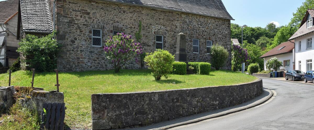 A stone church with a steep roof and a weather vane.