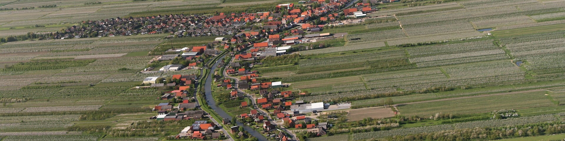 Luftaufnahme: der kleine Fluss, der das Bild teilt, ist die Lühe, der Ort links ist Steinkirchen, der Ort rechts ist Mittelnkirchen, der Ort vor der Elbe ist Grünendeich, in der Elbe dahinter liegt der Lühesand