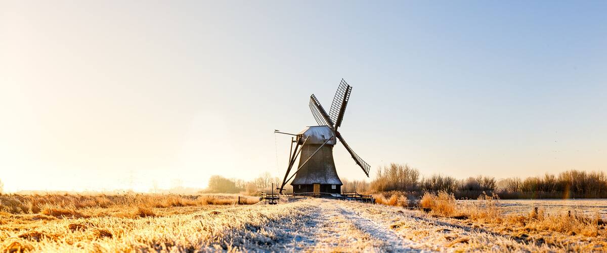 A windmill in a frosty field with a clear sky.